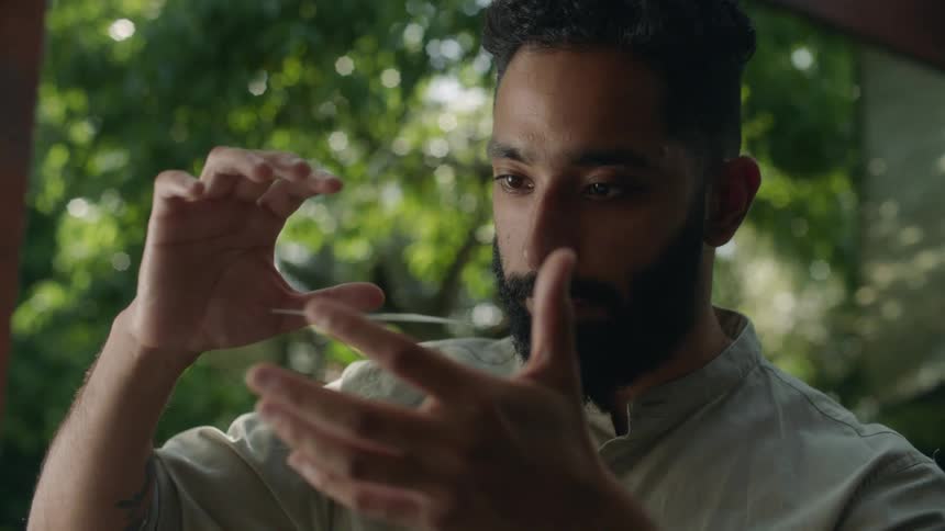 Young bearded magician makes a card float between his hands