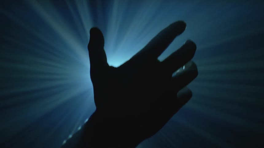 Light beams shine through a  raised hand