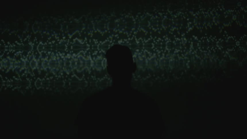 Silhouette of a man standing in front of a blinking screen
