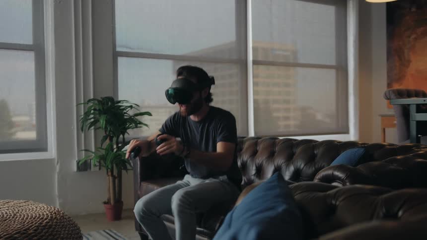 A man plays a virtual reality game on the couch