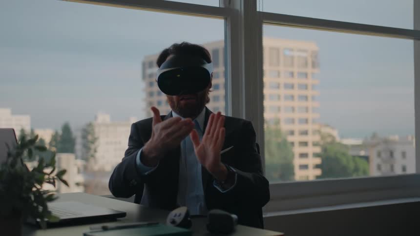 A man wears a virtual reality headset during a video call at his desk