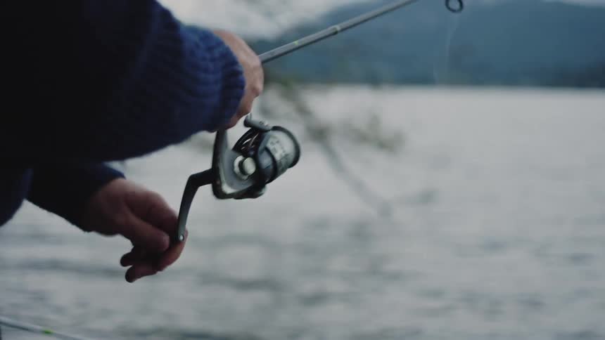 A man is fishing by himself outdoors on a lake