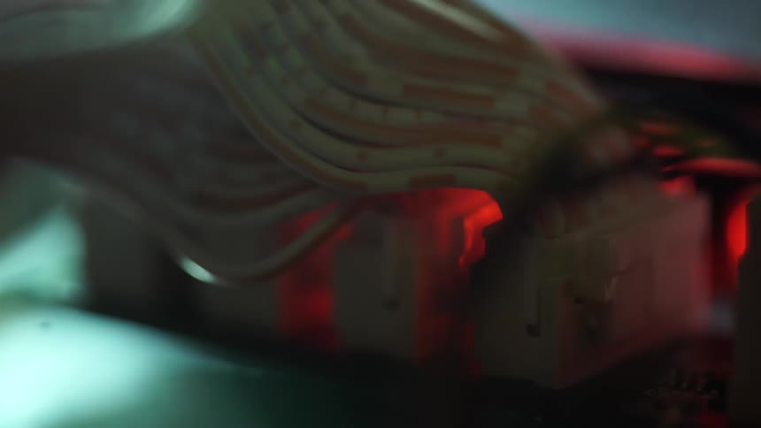 Colored lights glow and move inside a machine with electronic components and wires