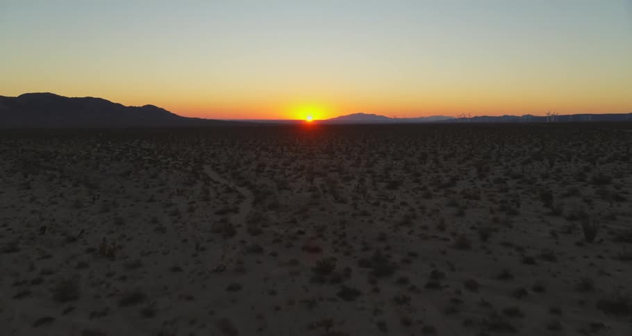 A sun setting on a mountain silhouette in the desert
