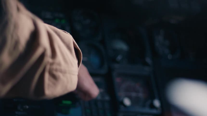 A person reaches forward and changes dials and gauges in front of him