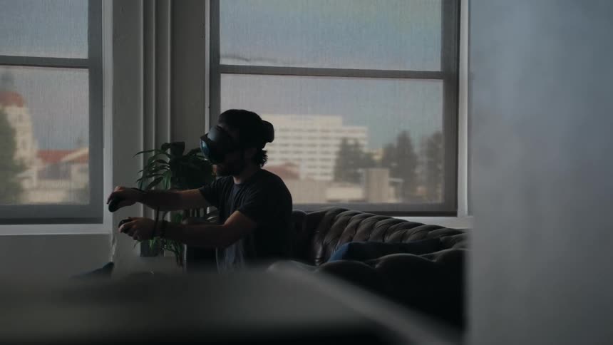 A man is playing video games and sitting indoors