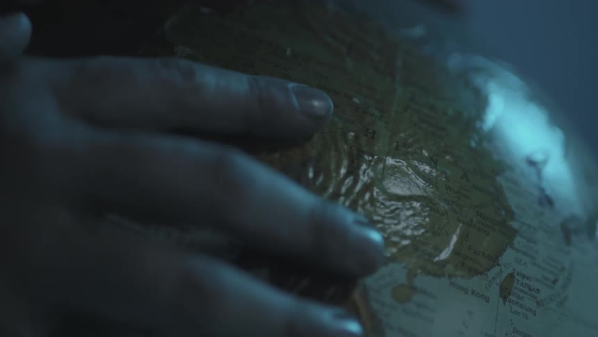 A hand is pulling back across the surface of a globe