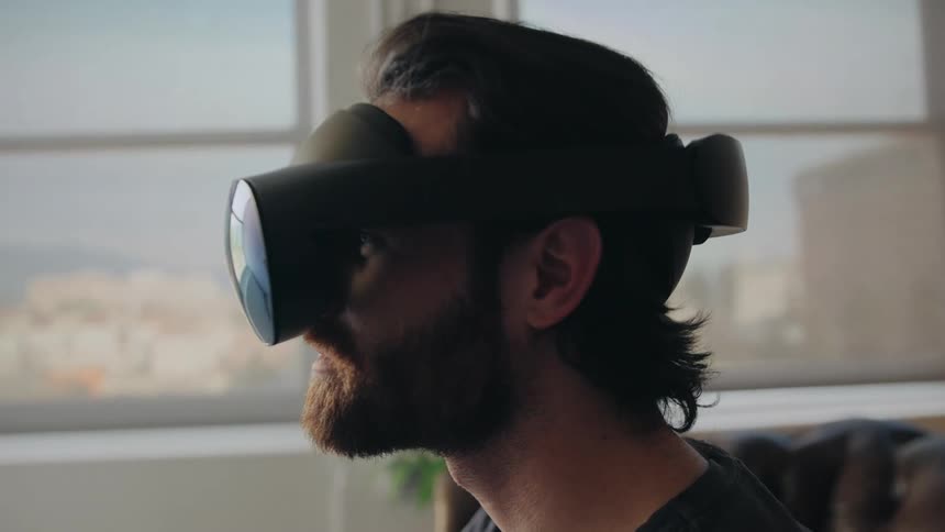 A man sitting in his living room wearing a virtual reality headset