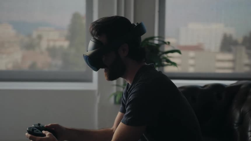 A man is sitting down and playing a virtual reality game