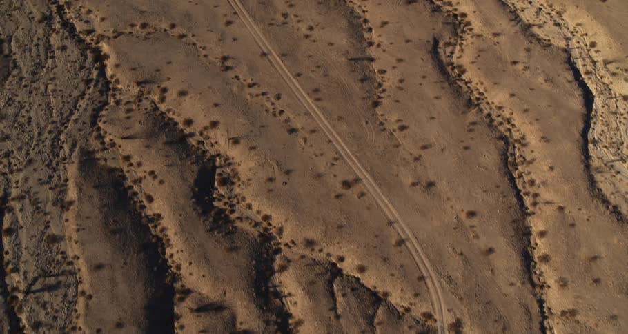 Narrow vehicle tracks lead across arid land