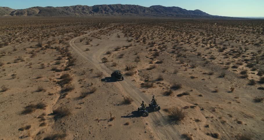 People are riding vehicles through a desert area