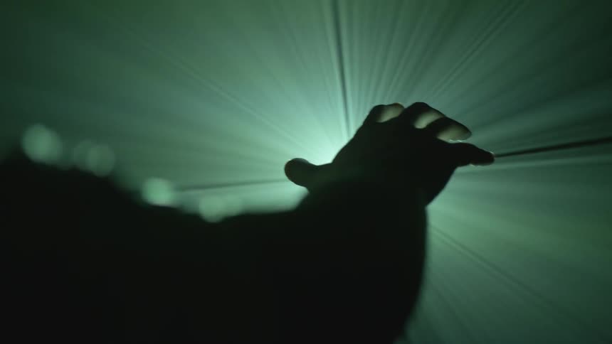 A man moves his hand in front of a light