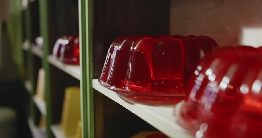 A red jelly shape dancing on a table its gelatinous body wobbling and jiggling in a mesmerizing dance