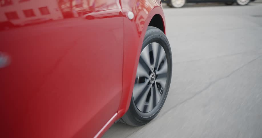 A red car traveling on a paved street