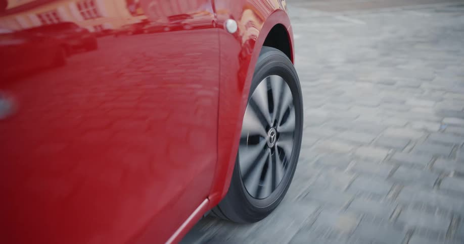 Red car drives on tiled road in the street