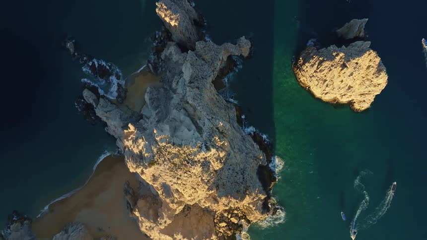 Speedboats sail past sea stacks in the ocean