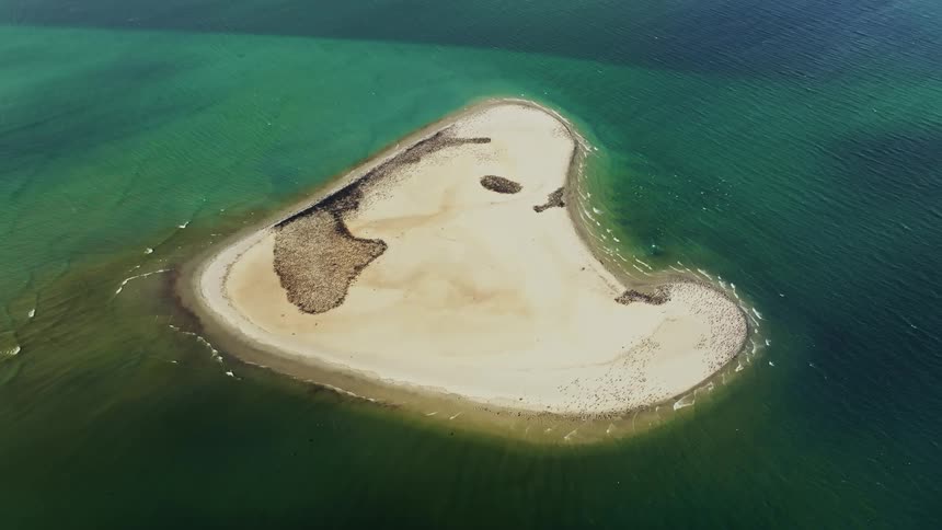 Aerial view of an island surrounded by ocean is displayed