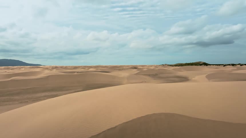 Vast and barren desert landscape dominates the view with a solitary hill