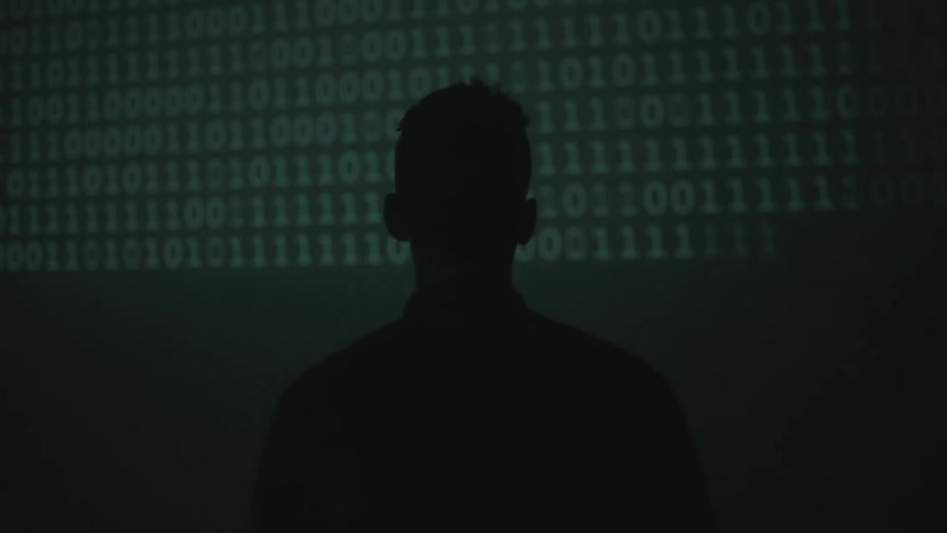 Silhouette of a man looking at flashing zeros and ones on a screen in front of him