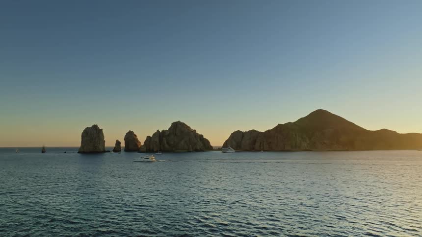 A boat is driving through the ocean water at dusk