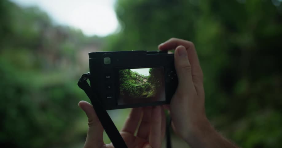 Man takes photos of buildings on green hill