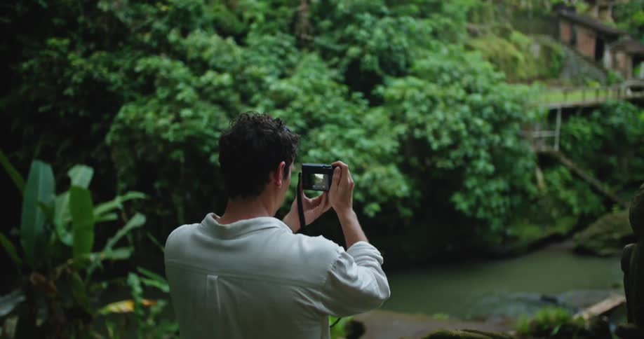 Photographer takes pictures of houses near a river on the tropical woods