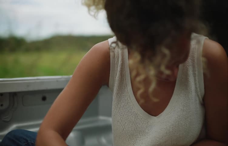 A woman is petting a dog as they ride in the back of the pickup truck