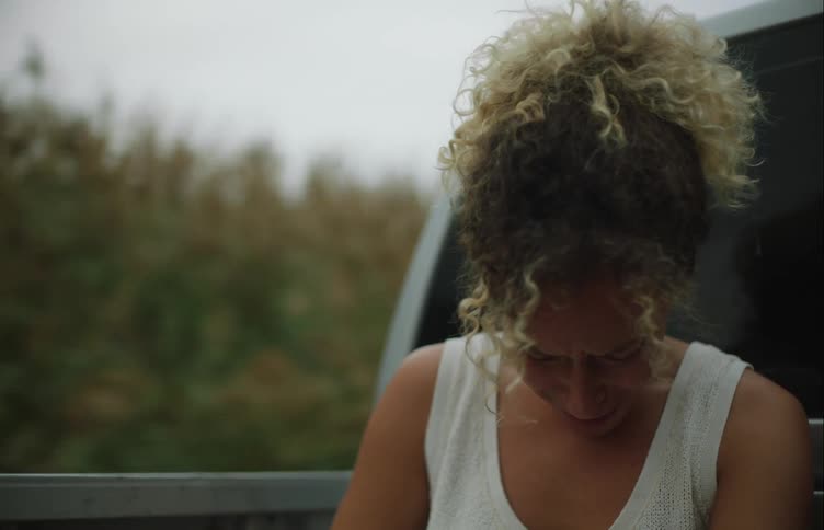 Woman riding in truck bed through countryside cries