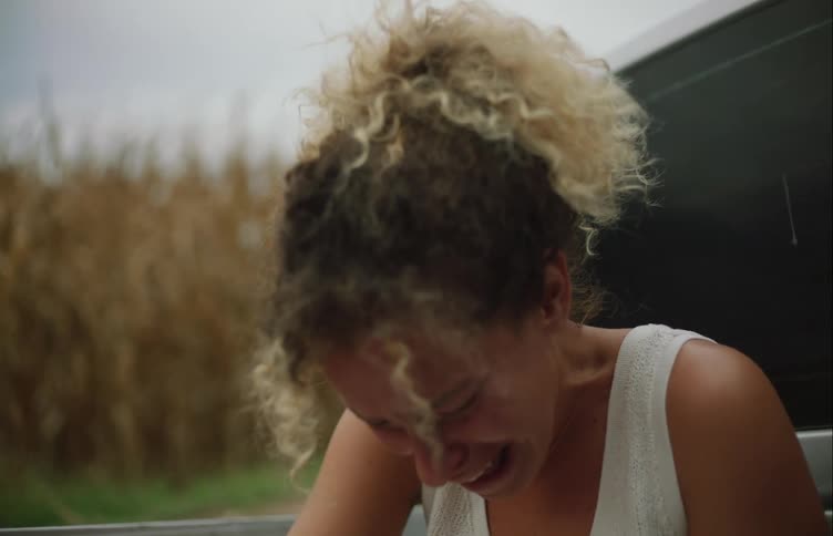 A woman with curly hair is incredibly sad and crying while outsie