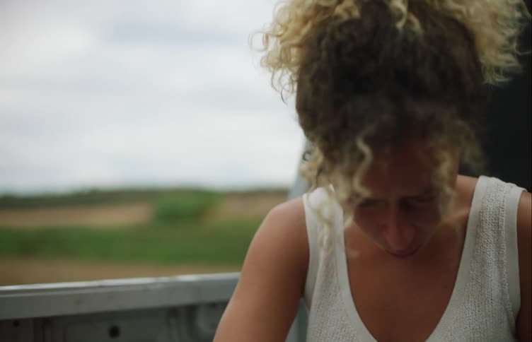 Woman holding a sick dog on her lap while riding on the back of a pickup truck