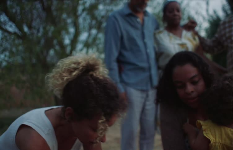 Family gather around the grave of a deceased pet in the countryside