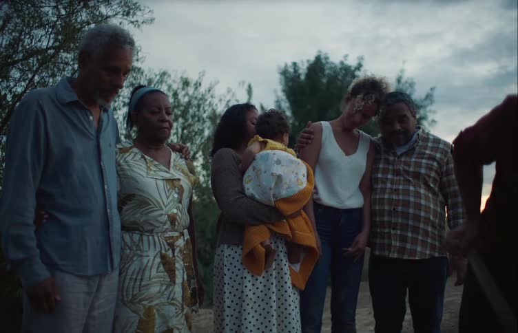 Family gathers pensively around a man digging a grave for a deceased dog