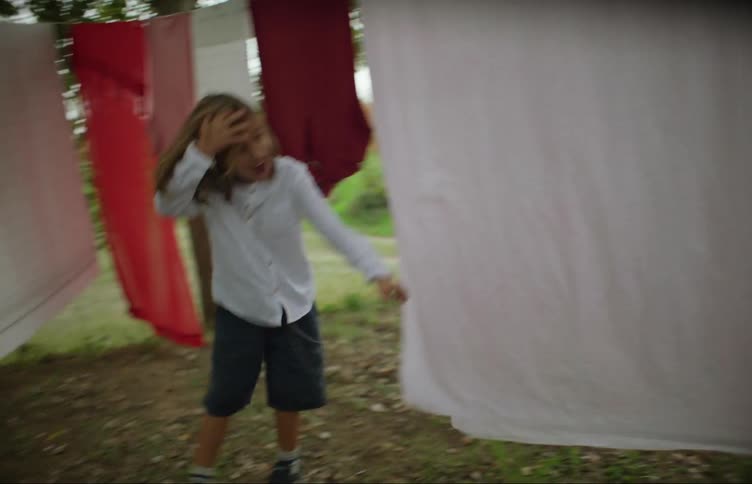 Girls play near laundry hanging on clothesline near driveway on farm