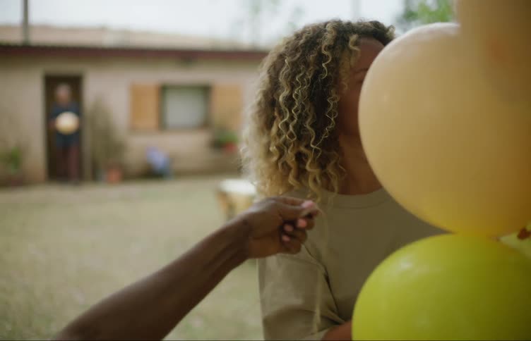 Happy woman decorates a tree with balloons in the backyard at home