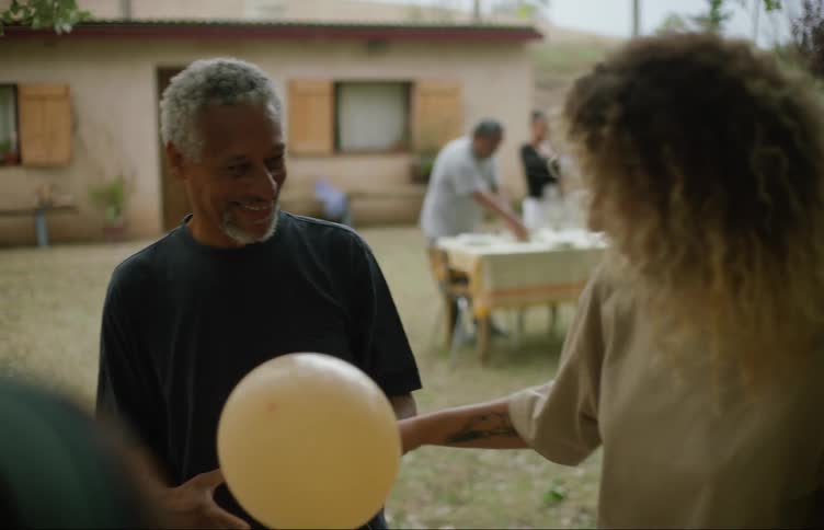A man rubs a balloon on a womans hair at a party outside