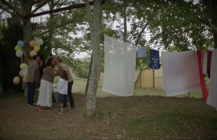 A couple and their child greet a family arriving for a party at their home