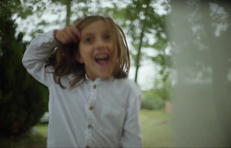 Girl runs and plays through laundry hanging on clothesline at farm