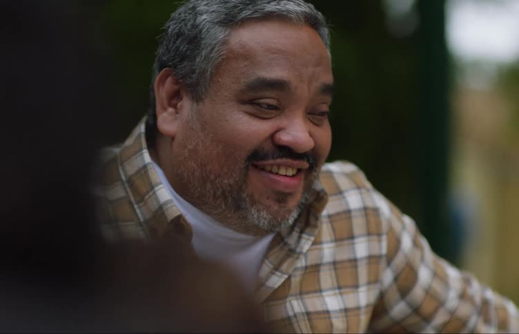 Older man sitting outdoors with friends gestures as he talks