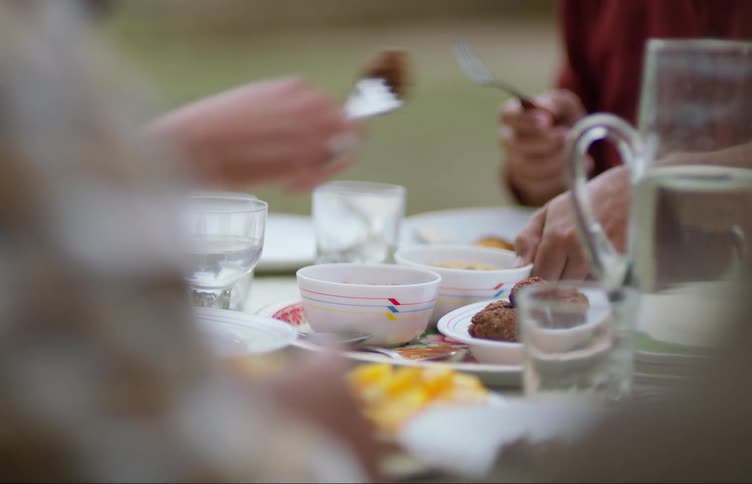 A family eats dinner at a full table outside