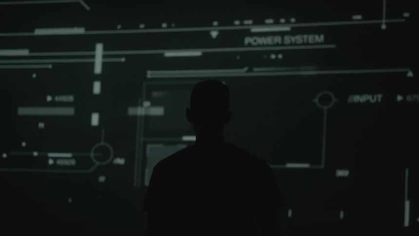 A man standing watching diagrams projected on a wall
