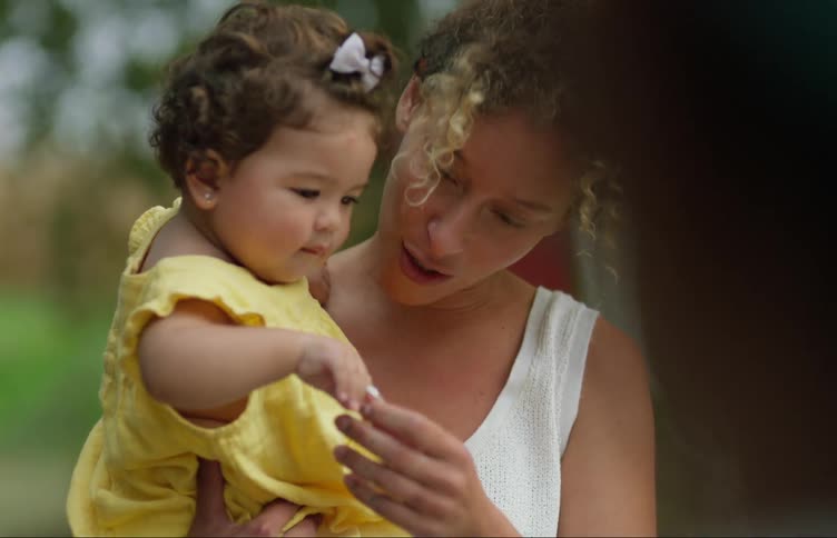 A woman talks to a small child while carrying the child in her arms