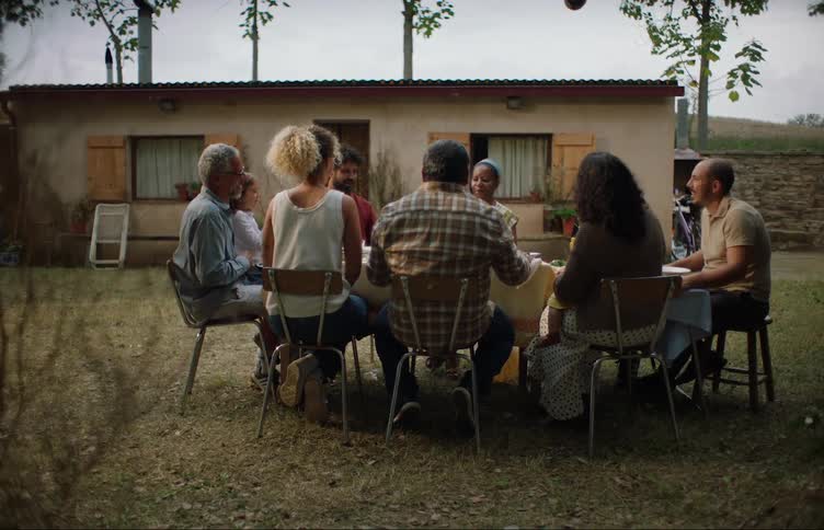 Family and friends sitting around table outdoors in the backyard