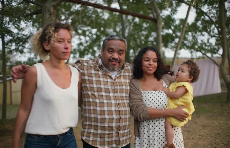 A woman poses with family for a photo but is visibly preoccupied and runs off
