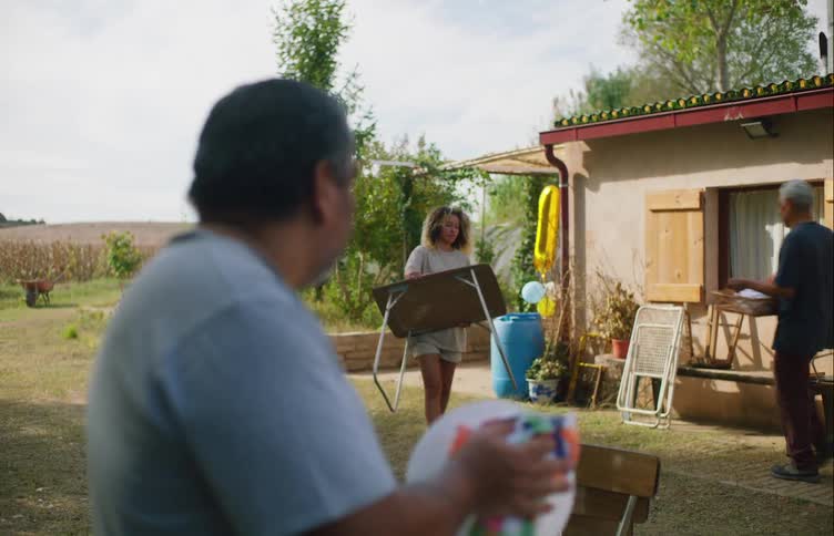 People move around backyard of rural home carrying things and cleaning up
