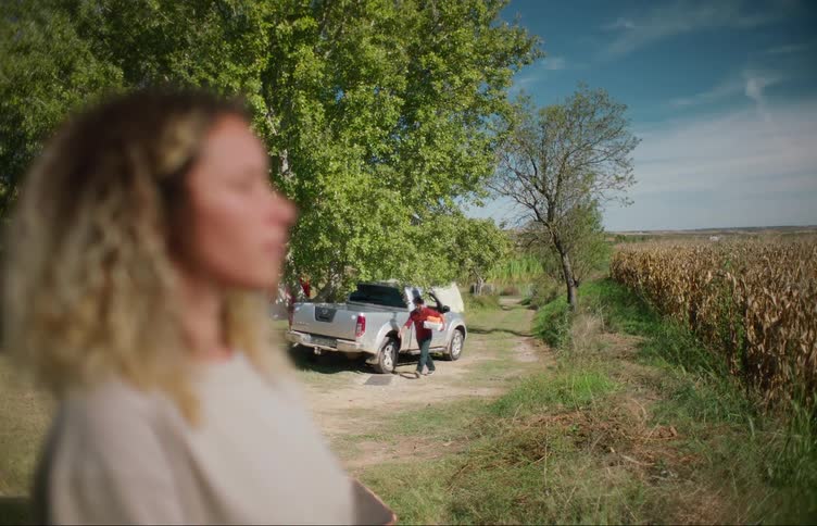 A man gets out of his pickup truck with boxes and walks up to a woman standing outside