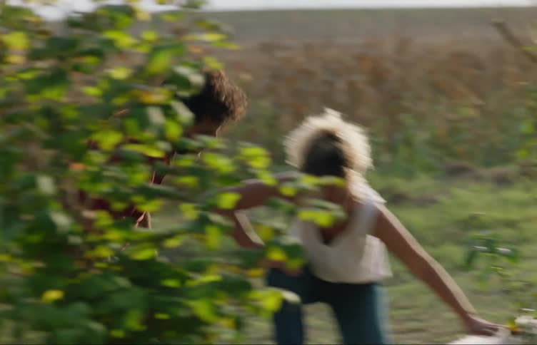A couple hurriedly carry an injured dog to a pickup truck on a farm