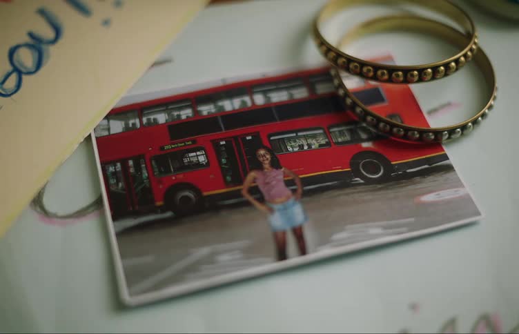 Picture laying on a table of a girl in front of a red double decker bus
