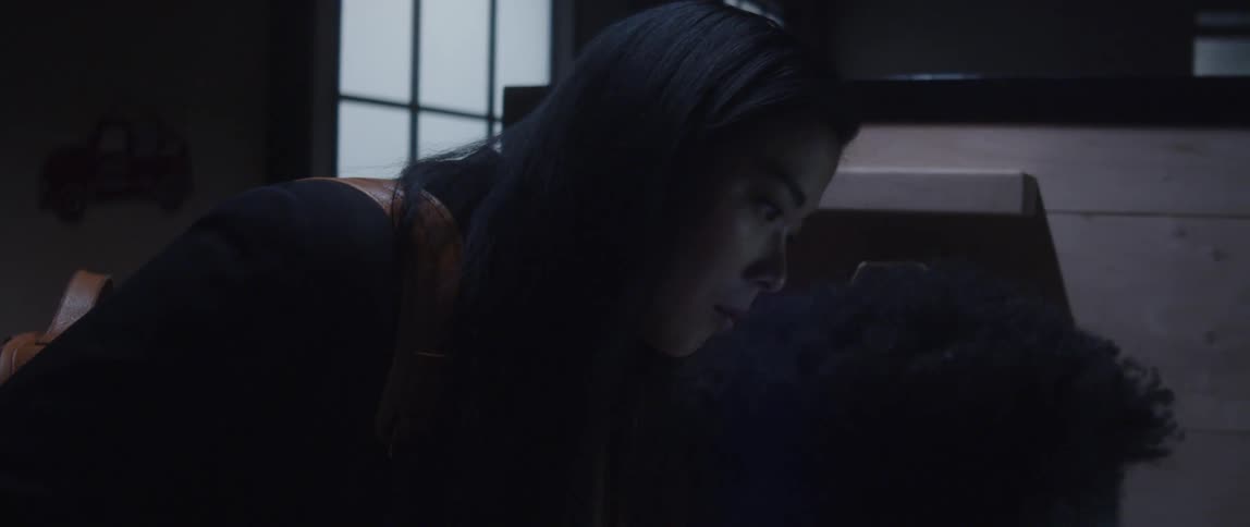 A man is sitting at a desk in front of a computer as a woman stands next to him looking at the monitor