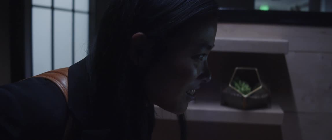 A woman standing by a cubicle and talking to someone while nodding and smiling