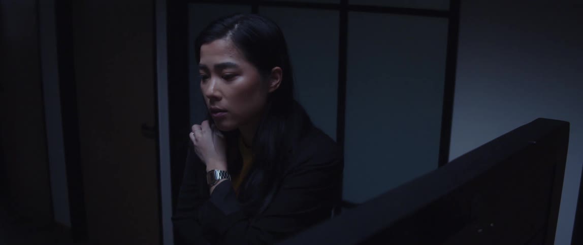 A woman standing nodding her head talking to someone while she adjusts the leather bag on her shoulder